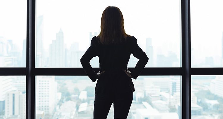 Woman stood with back to camera, looking out of window