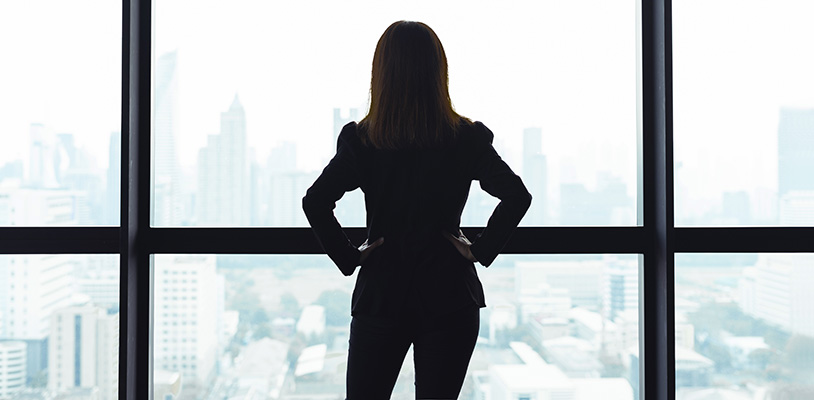 Woman stood with back to camera, looking out of window