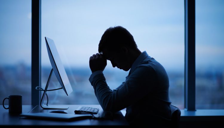 A stressed CEO sitting at a desk by a window