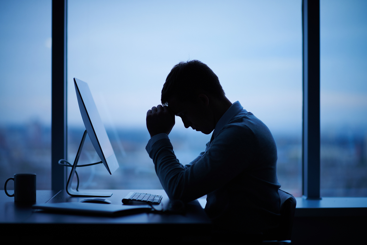 A stressed CEO sitting at a desk by a window