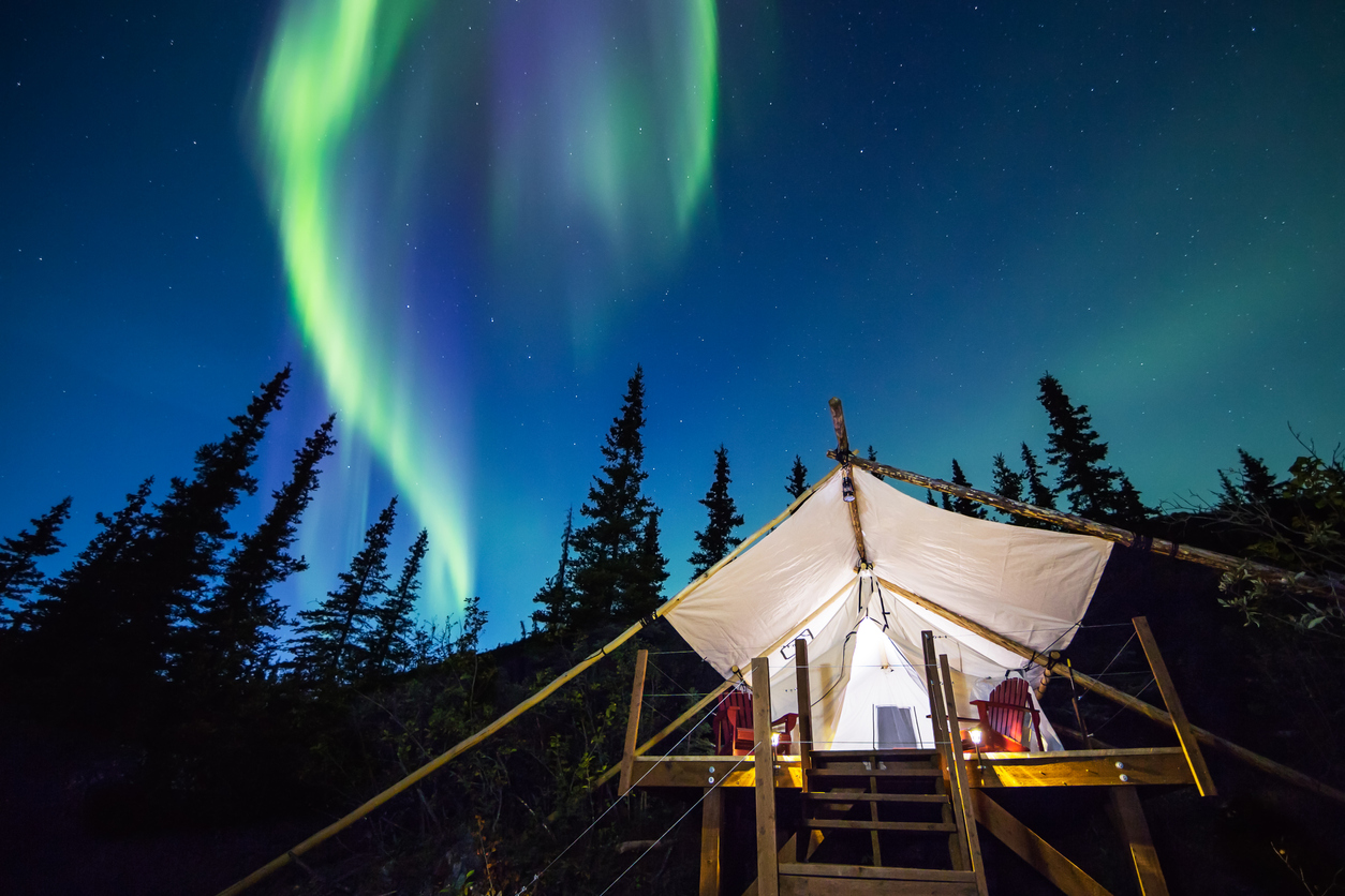Aurora Borealis above luxury camping tent in Alaska