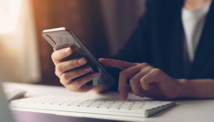 Woman using smartphone in home office