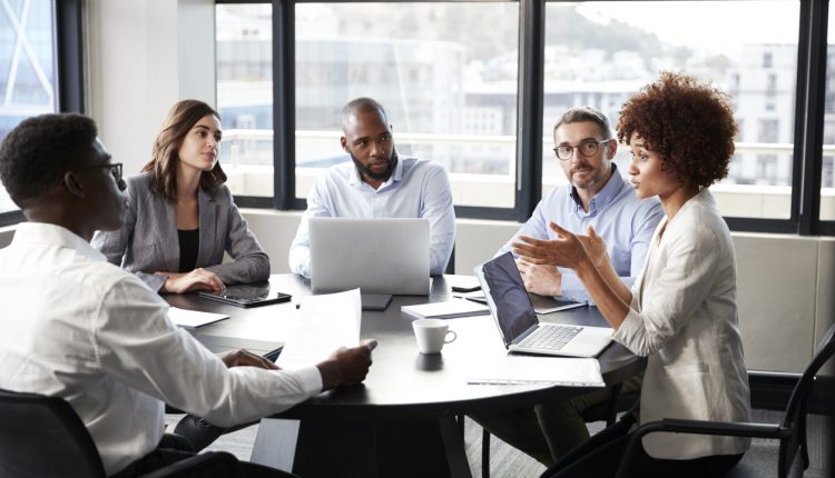 Businesswoman addressing executive colleagues in boardroom meeting