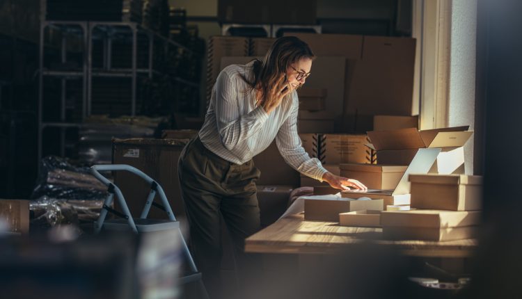 Businesswoman in warehouse taking orders on phone