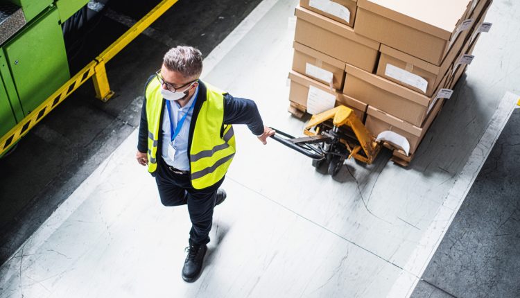 Masked man moving boxes in warehouse