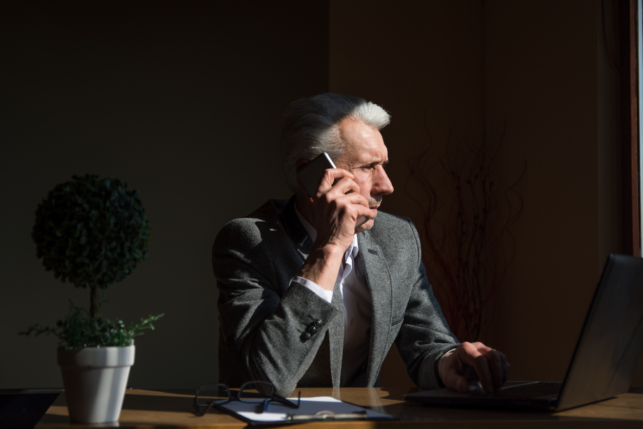 Older businessman talking on the phone in home office