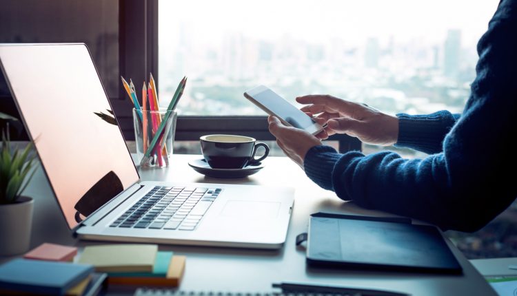 Businessman using laptop and smartphone in skyscraper office