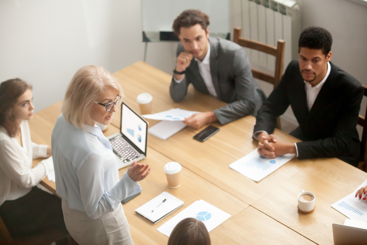 Businesswoman speaking at meeting with senior colleagues