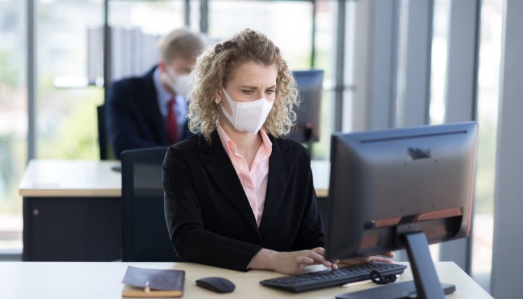 Businesswoman wearing mask, working at an office desk