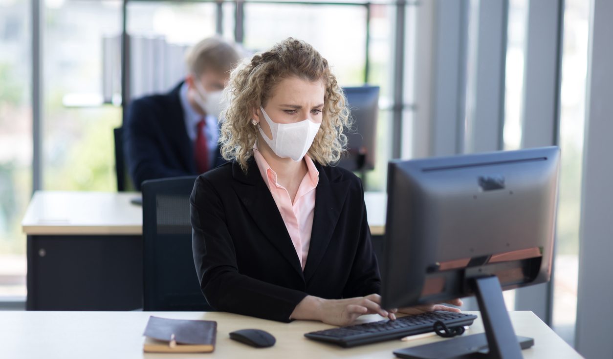 Businesswoman wearing mask, working at an office desk