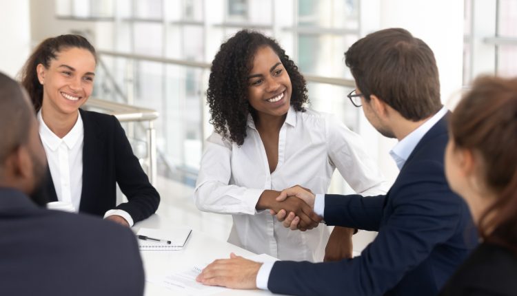 Diverse business partners shaking hands in boardroom