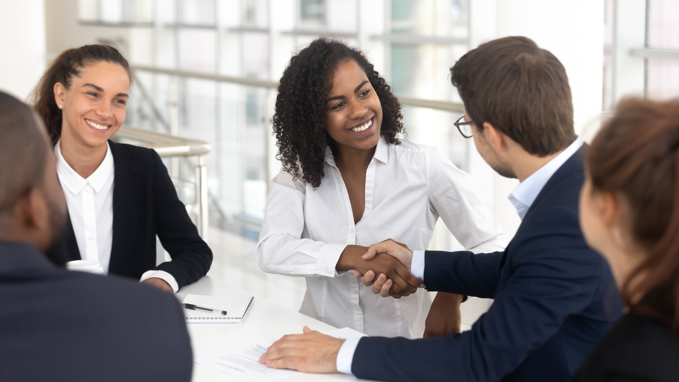 Diverse business partners shaking hands in boardroom