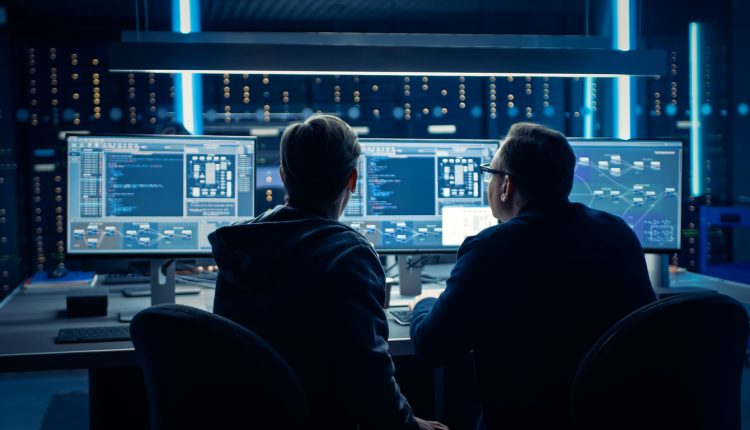 Two cybersecurity professionals looking at multiple monitors