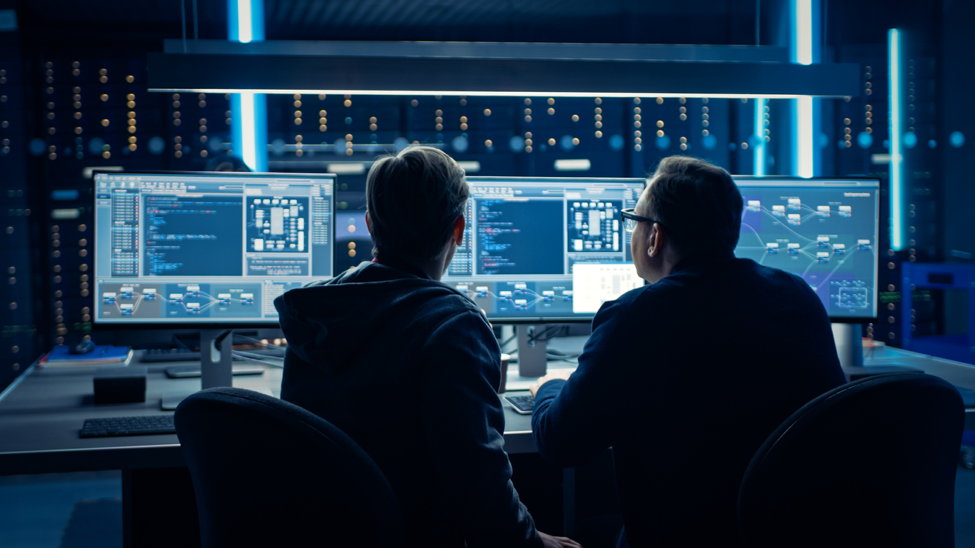 Two cybersecurity professionals looking at multiple monitors