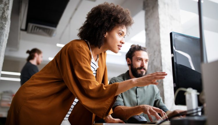 Two corporate employees reviewing data on a computer monitor