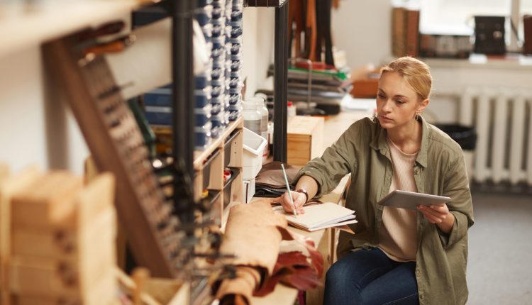 Young woman in workshop writing notes