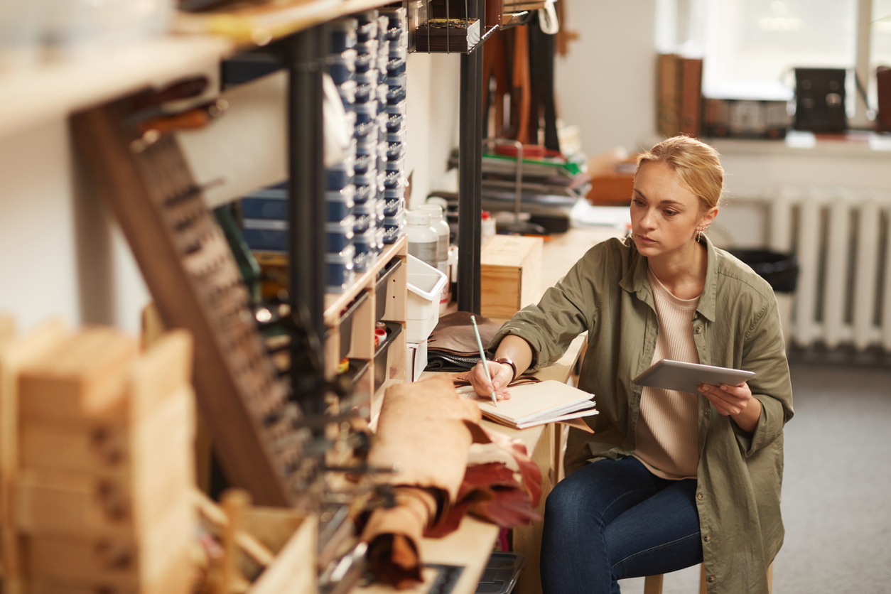 Young woman in workshop writing notes