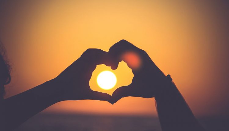 Hands outlining the sun with a heart image