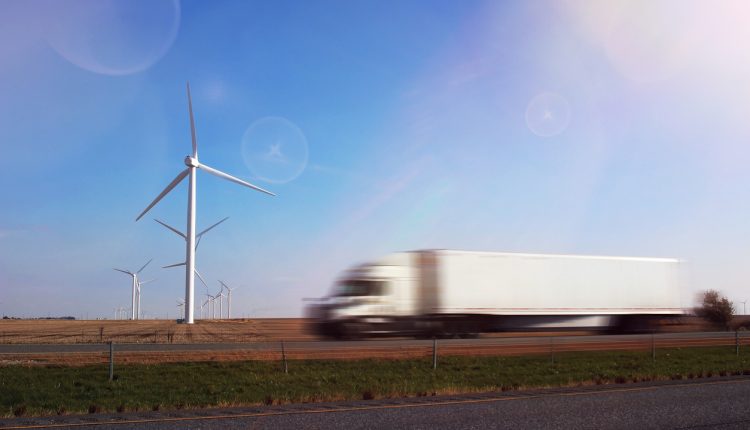 Truck driving by wind turbine; sustainable business operations