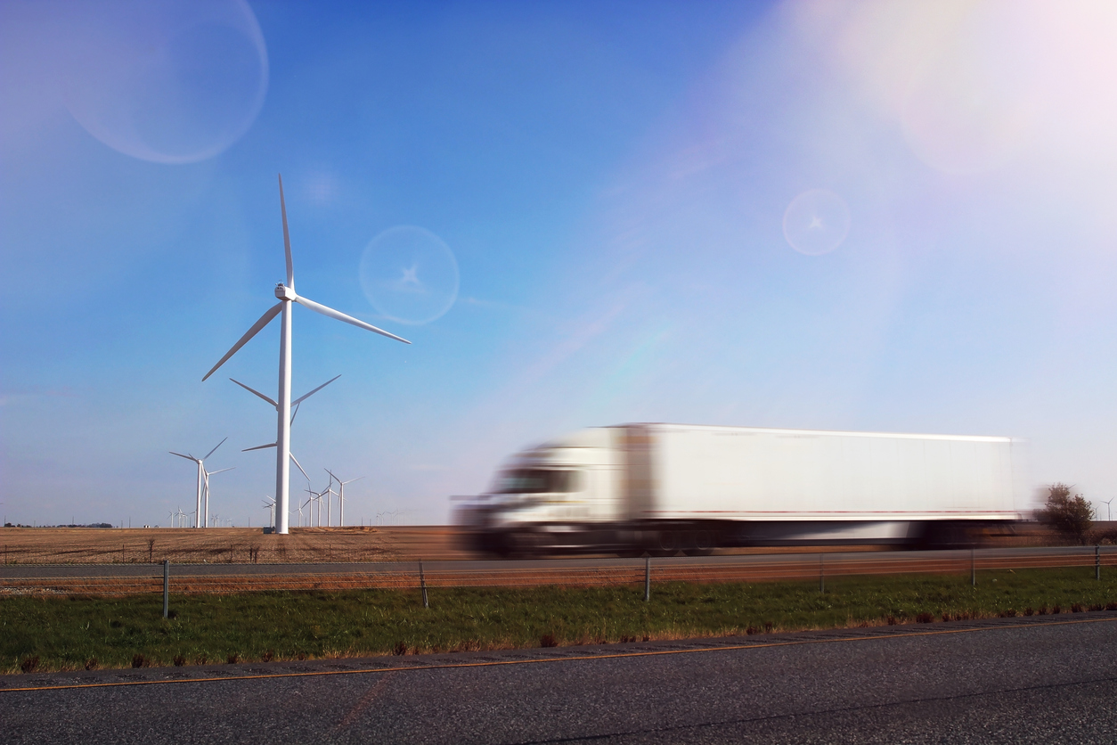 Truck driving by wind turbine; sustainable business operations
