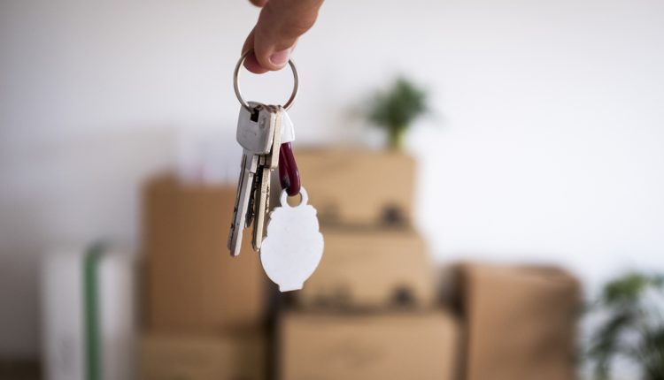 Close-up of the keys of the new empty apartment with moving boxes on the floor