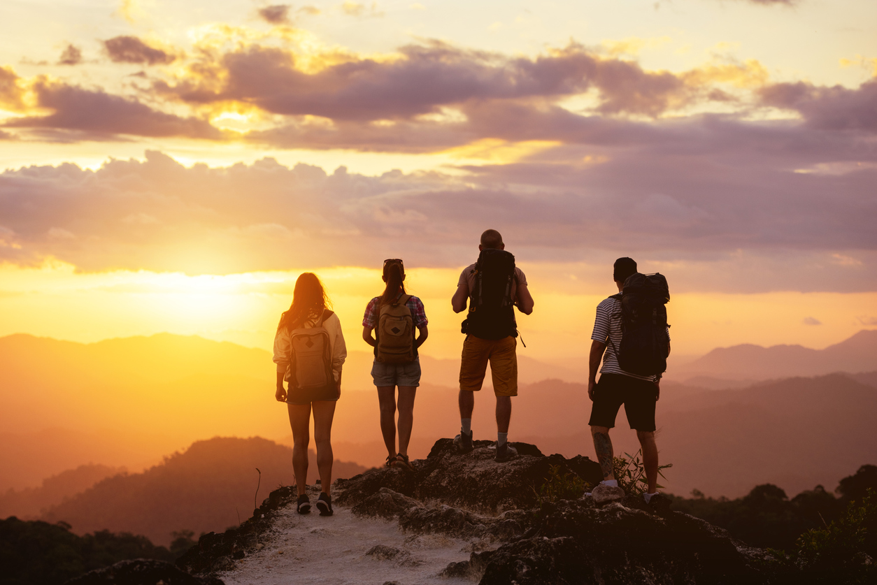 Group of people reaching top of mountain