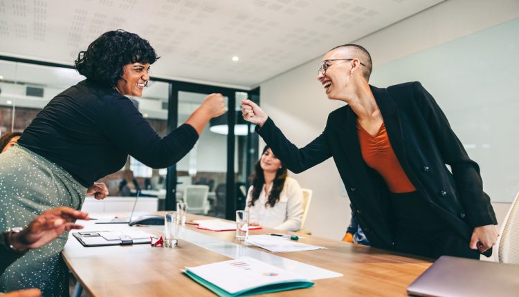 Satisfied employees fist-bumping in office