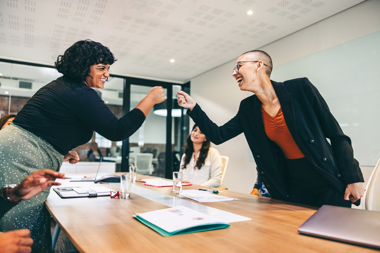 Satisfied employees fist-bumping in office