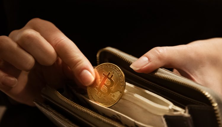 Woman puts gold bitcoin coin in her purse, close up hands shot