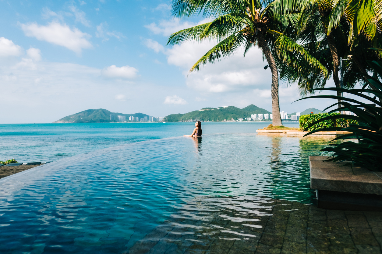 Young woman enjoying view from luxury swimming pool