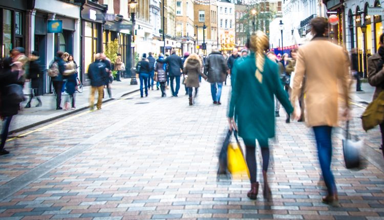 Shoppers walking down the high street holding hands and carrying shopping bags