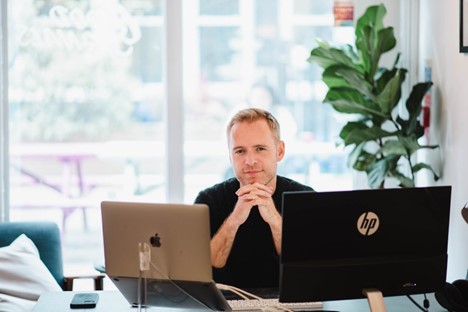 Michael Chidzey sitting at a desk with computers.