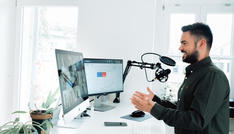 Man hosting a remote conferencing call using two screens