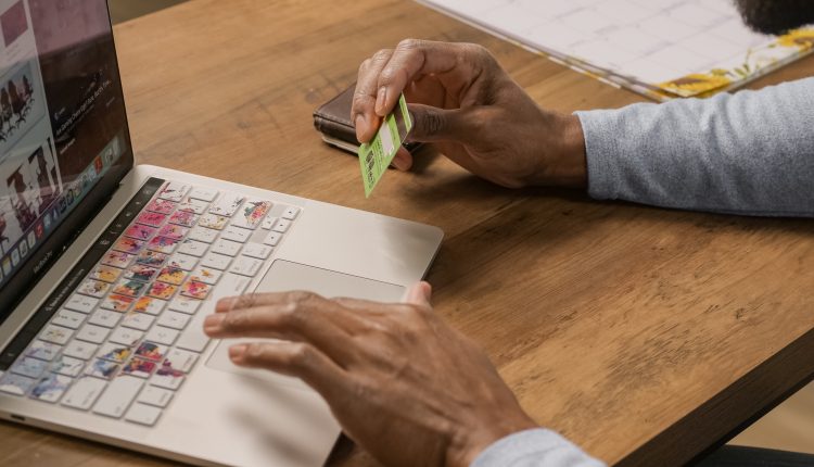 A businessman using a credit card to pay on their laptop