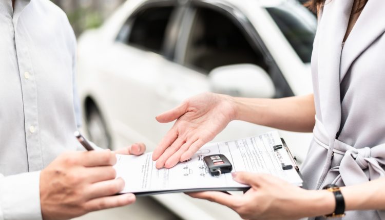 Automotive business, car sale or rental concept : Happy customer with car dealer agent making deal and signing on agreement document contract in auto showroom or car dealer office.