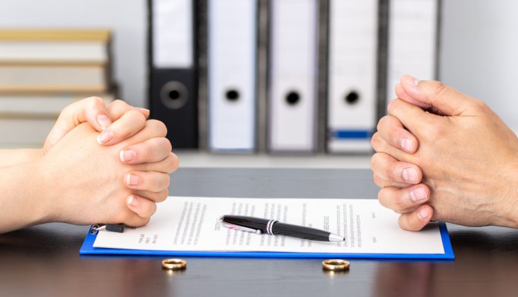 Hands of wife and husband signing divorce documents or premarital agreement at the lawyer's office