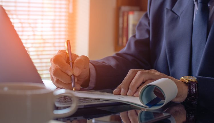 Businessman hand writing and signing white empty bank checkbookm Payment by check, paycheck, payroll , cheque sign conceptual.