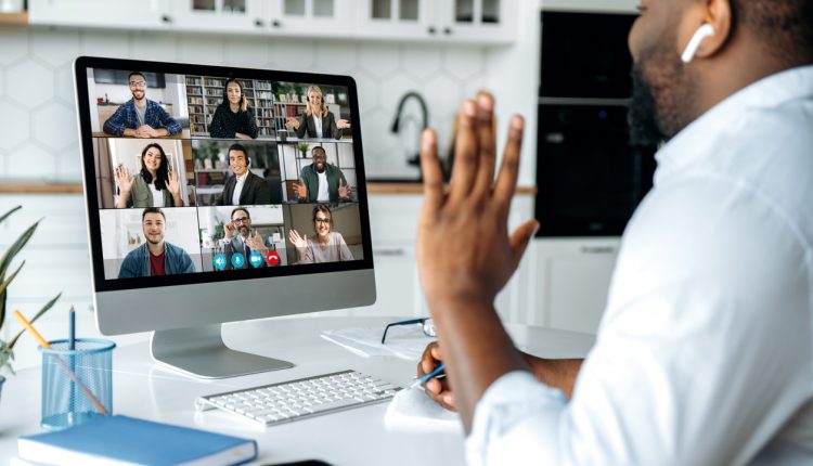 Video call, online conference. Over shoulder view of african american man at computer screen with multinational group of successful business people, virtual business meeting, work from home concept