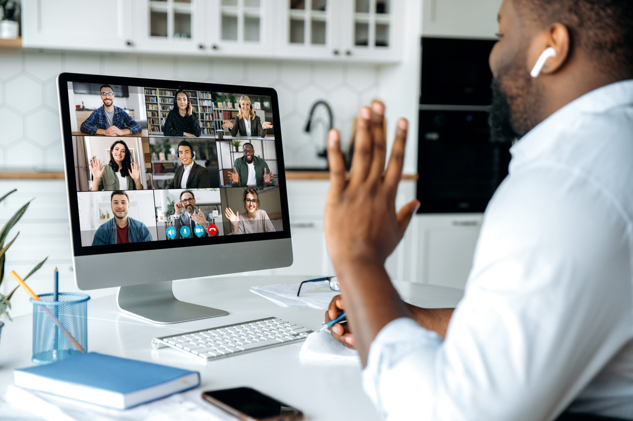 Video call, online conference. Over shoulder view of african american man at computer screen with multinational group of successful business people, virtual business meeting, work from home concept