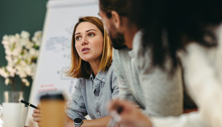 Young businesswoman having a discussion with her colleagues in a boardroom. Creative young businesswoman sharing her ideas during a meeting in a modern office.