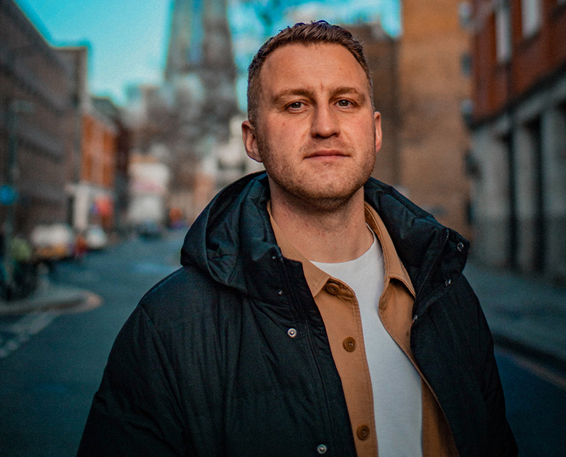 Tom Bairstow in a street at sundown.