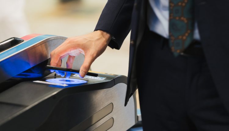 Businessmen passing through ticket gates with touchless technology (hands, ups, body parts)