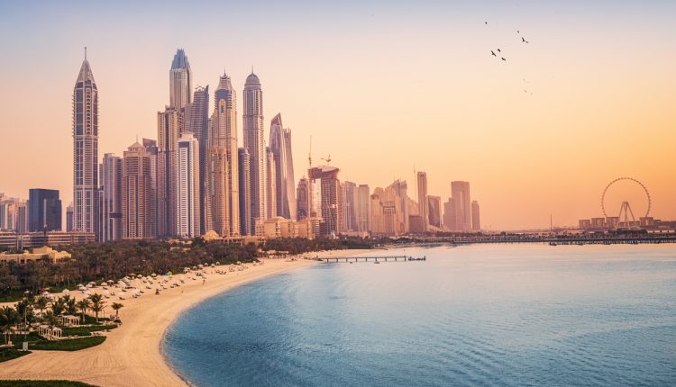 Sunset view of the Dubai Marina and JBR area and the famous Ferris Wheel and golden sand beaches in the Persian Gulf. Holidays and vacations in the UAE