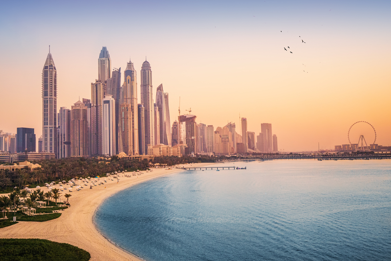 Sunset view of the Dubai Marina and JBR area and the famous Ferris Wheel and golden sand beaches in the Persian Gulf. Holidays and vacations in the UAE