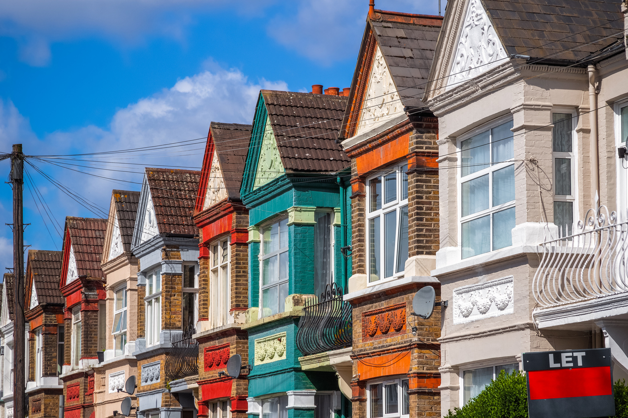 A row of colourful terraced houses around Kensal Rise in London with a LET sign