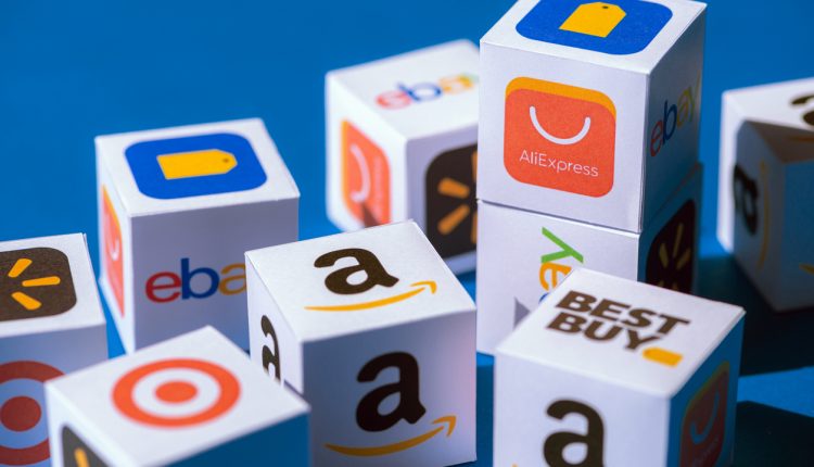 A paper cubes collection with printed logos of eCommerce corporations and online retail stores, such as AliExpress, WallMart, eBay, Amazon, and others.