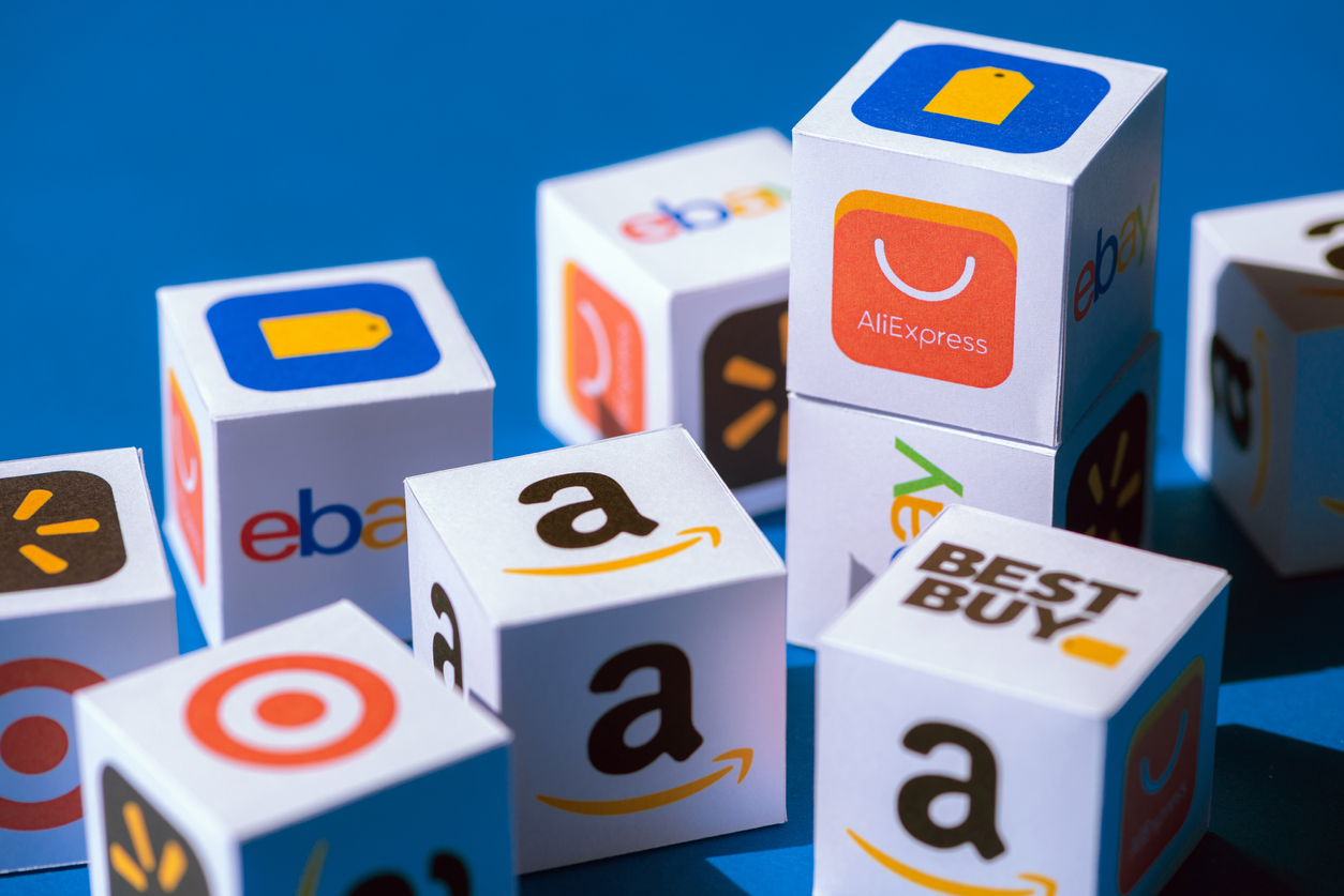 A paper cubes collection with printed logos of eCommerce corporations and online retail stores, such as AliExpress, WallMart, eBay, Amazon, and others.