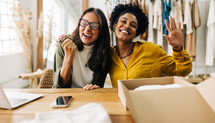 Ecommerce business owners celebrating their success as young entrepreneurs in retail. Two business women making teamwork a priority as they run an online clothing store together.