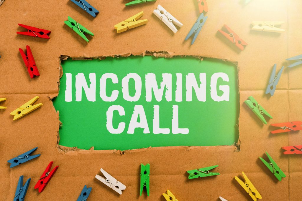 Hand writing sign Incoming Call, Concept meaning Inbound Received Caller ID Telephone Voicemail Vidcall Important Ideas Written Under Ripped Cardboard With Colored Pegs Around.