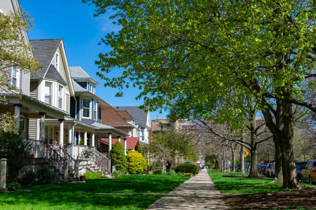 A row of old wooden homes with front lawns and a sidewalk in the North Center neighborhood of Chicago
